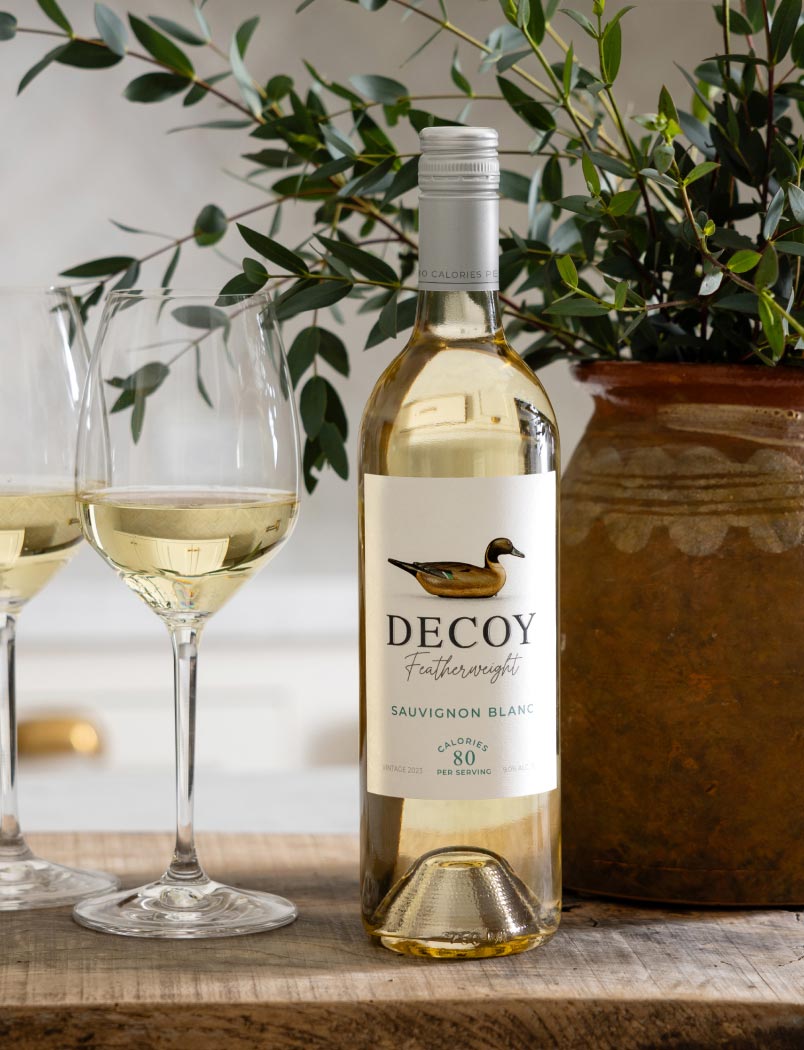 Decoy Featherweight California Sauvignon Blanc with two wine glasses on a table