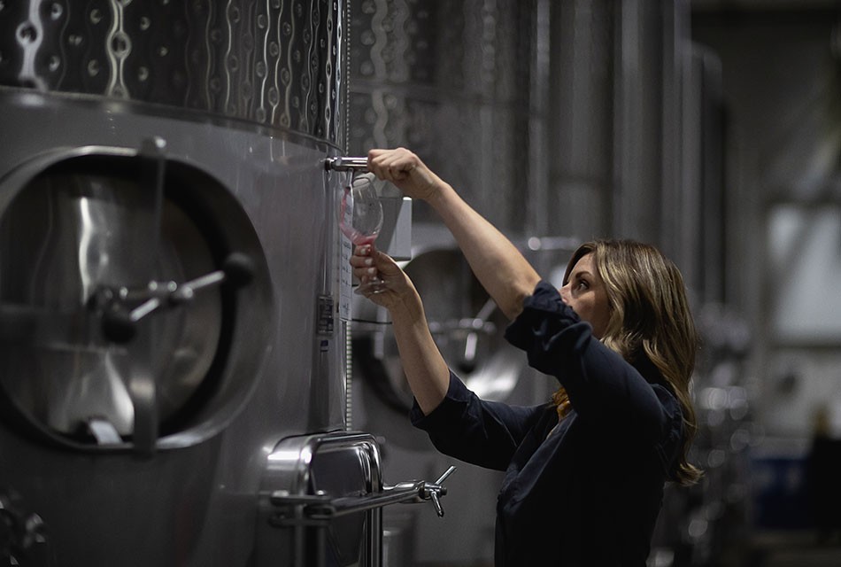 Winemaker examining the blend from a fermentation tank